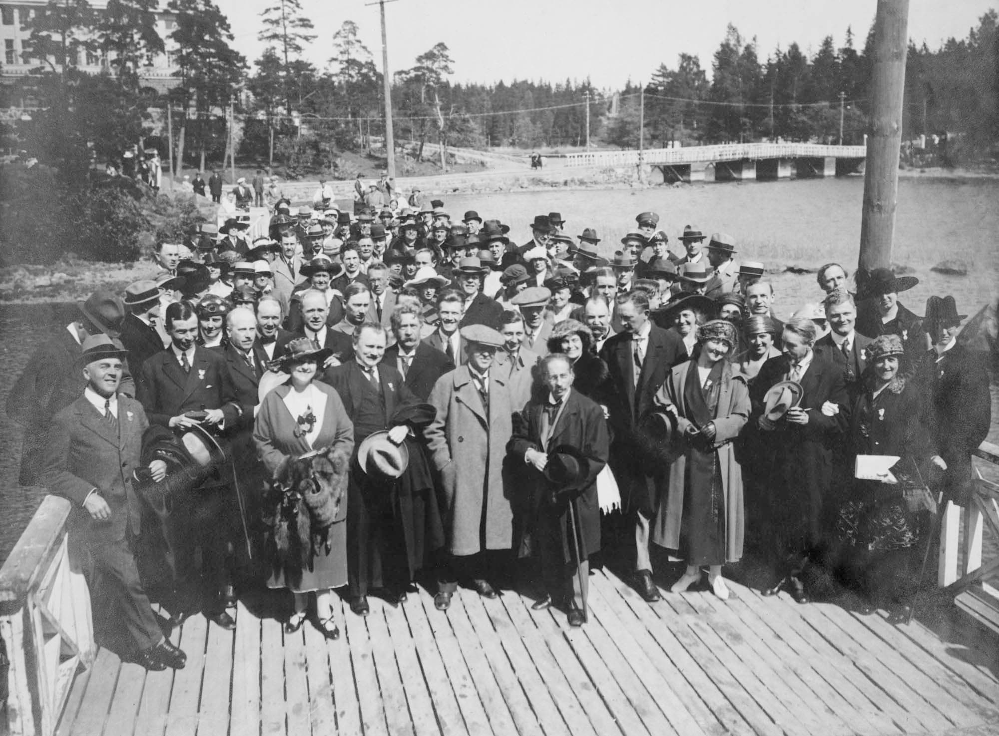 Den Nordiske Musikfest i Helsingfors den 20.-28.5.1921. Carl Nielsen står forrest i midten med hat. På hver side af ham ses Johan Halvorsen og Victor Bendix. Omtrent henne ved stolpen til højre står Frederik Schnedler-Petersen (med hatten i hånden) og Poul Schierbeck. Længst til højre Peder Gram.