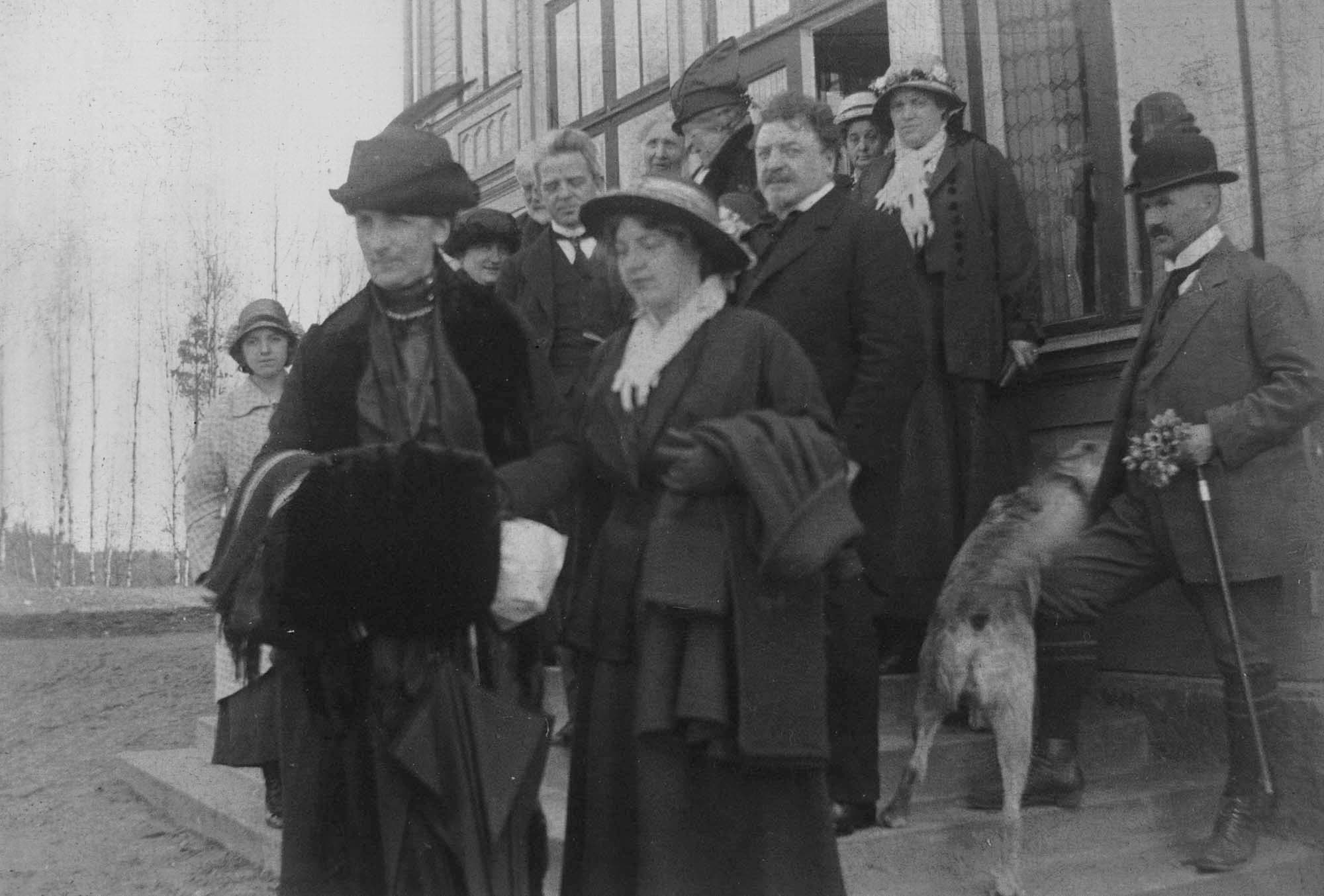 Carl Nielsen og Sophus Claussen ved siden af hinanden midt på trappen. Eneste eksisterende billede af de to sammen? Til venstre bag Claussen Anne Marie Carl-Nielsen i profil, til højre Claussens kone Anna Clausen. Forrest i billede damerne Elisabeth Dons og Johanne Feilberg, som var med ægteparret Nielsen i Småland i påsken 1916.