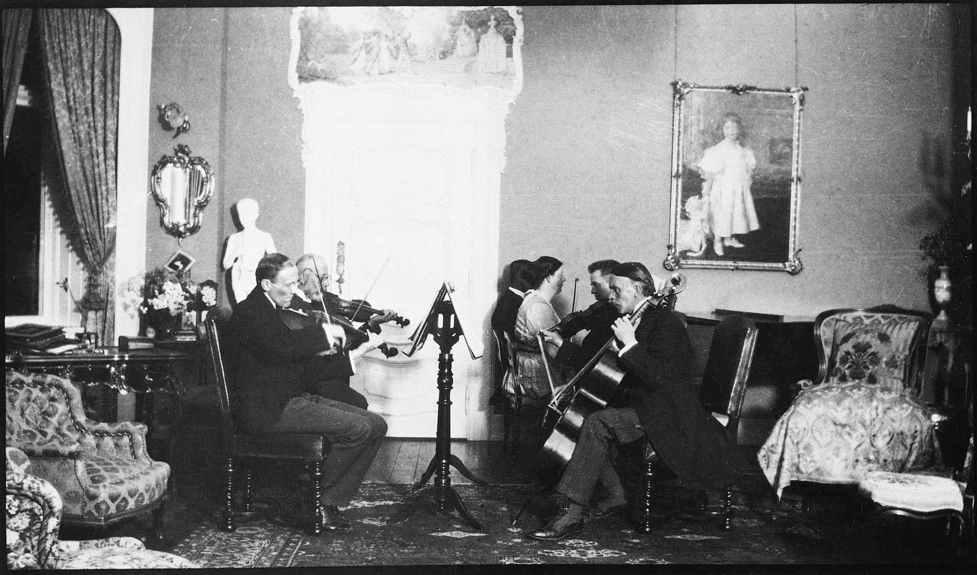 Kammermusik på Henriksholm i Vedbæk hos grosserer Carl Henriques Melchior. Til højre Carl Bretton-Meyer på cello og Carl Nielsen på violin. På væggen P.S. Krøyers maleri af Carl Melchiors datter Helga. Årstal ukendt.