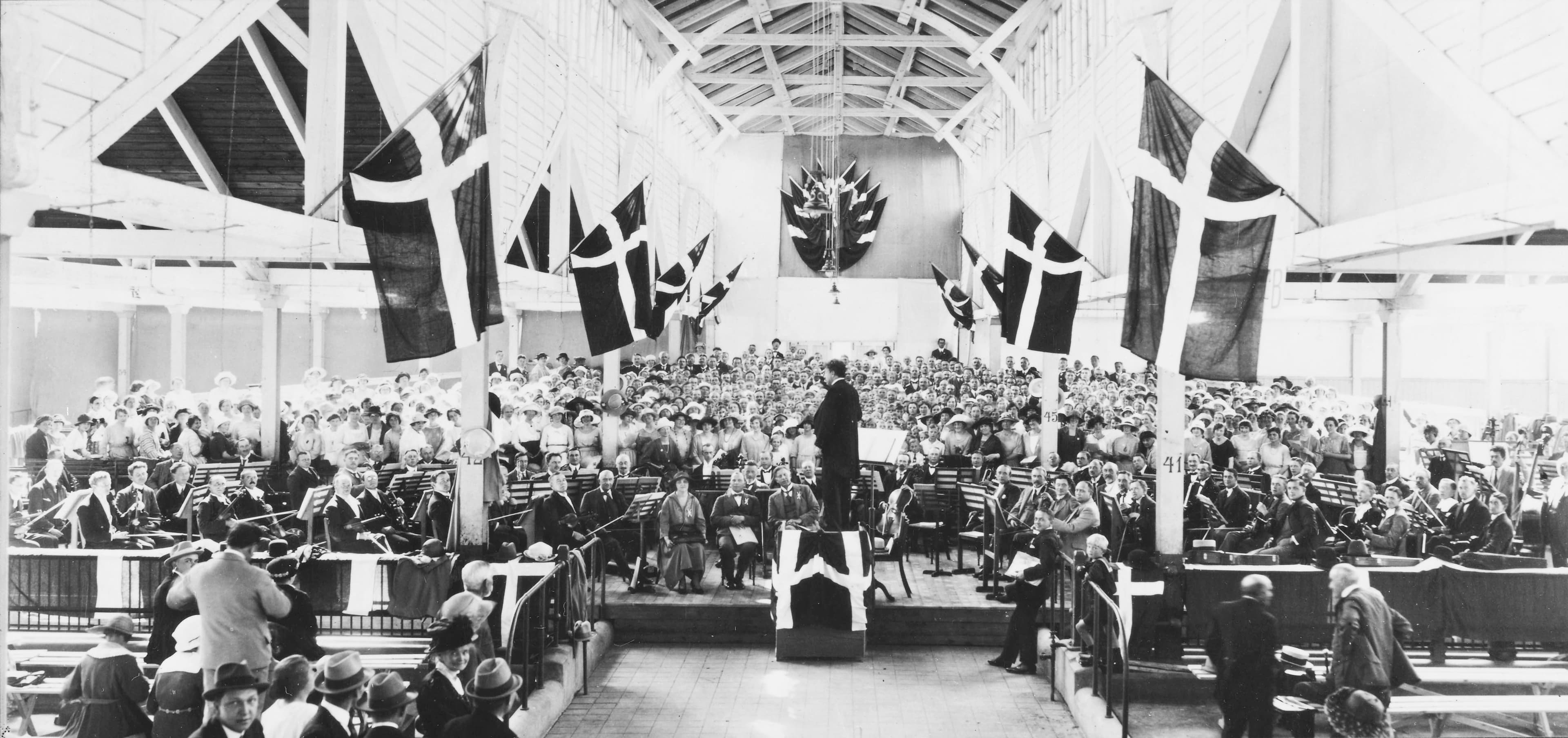 Kor og orkester under Georg Høebergs ledelse forud for uropførelsen af Fynsk Foraar lørdag 8.7.1922 i Odense under Dansk Korforenings tredje landssangstævne. Ved opførelsen, som fandt sted i kvægtorvshallen på Rugårdsvej, medvirkede ca. 900 sangere. Pressefoto i Fyens Stiftstidende mandag den 10.7.1922.