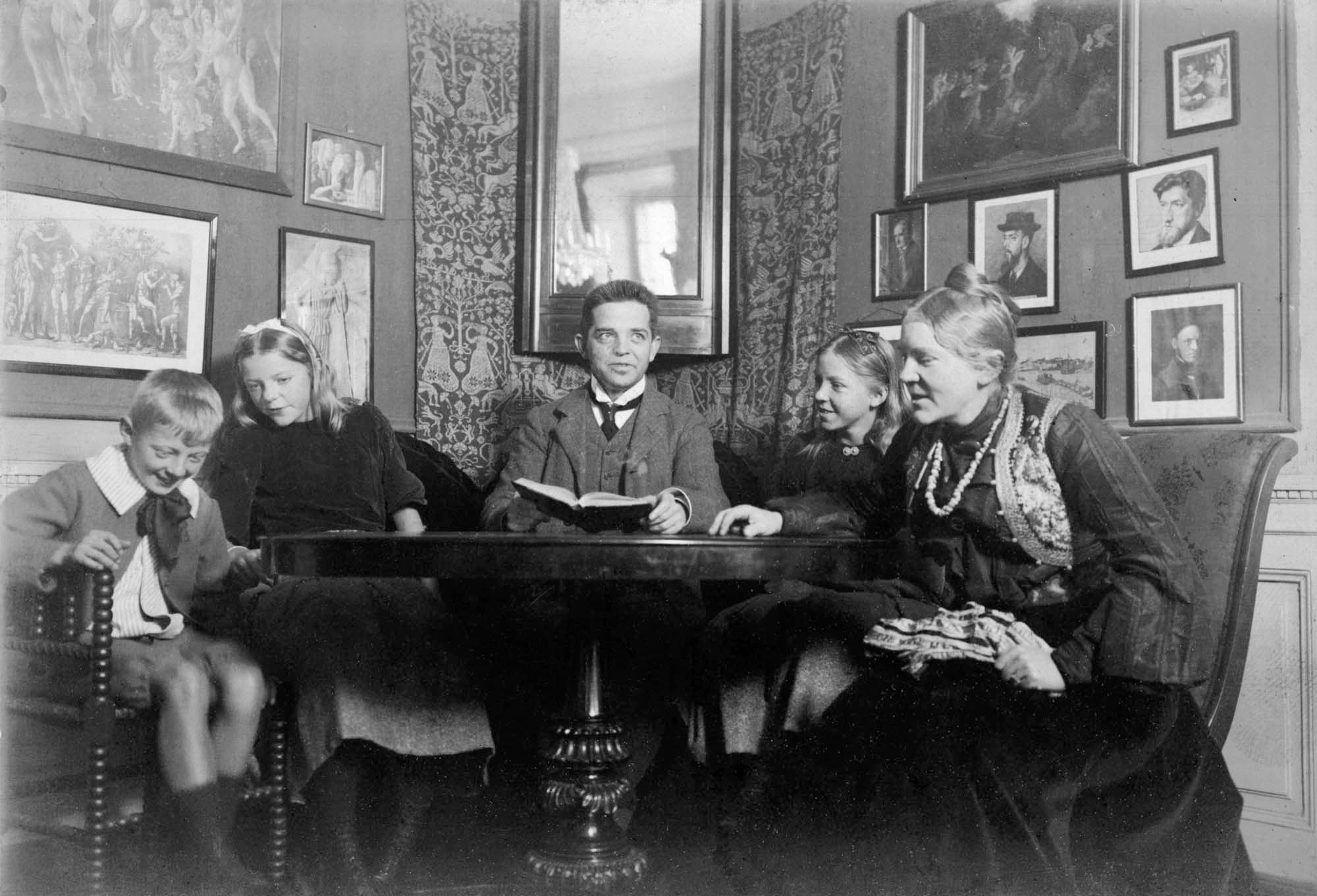 Dette og næste billede: I lejligheden på Toldbodvej. ”Far skulle sidde med en bog (han ligner en præst på dette billede). Vores lille hund sprang gøende rundt.” AMT s. 50. Fotograf Viggo Neergaard.