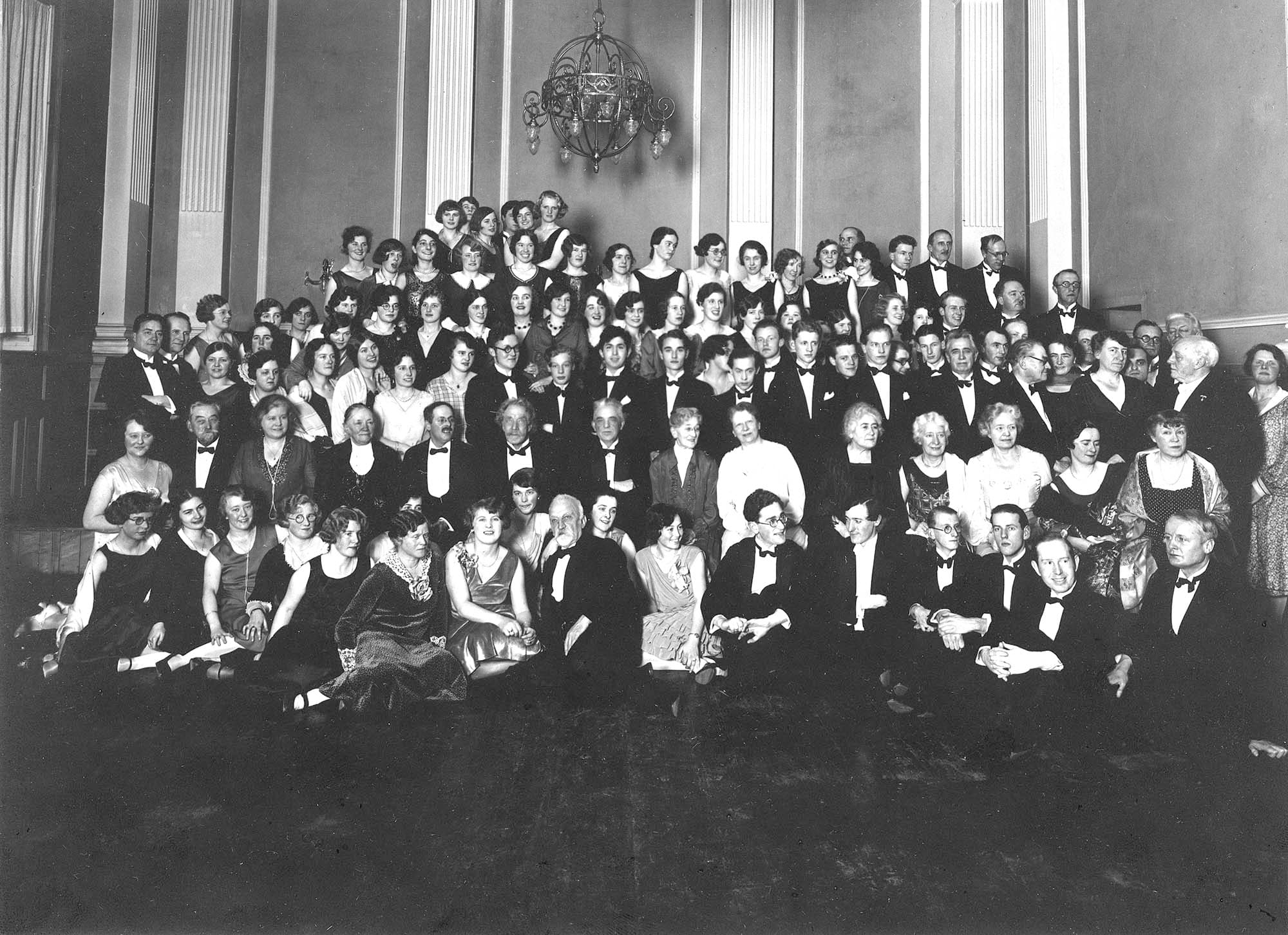 December 1930, juleafslutningsfesten i Det Kongelige Danske Musikkonservatorium. Midt i forreste række sidder A.P. Weis og Herman D. Koppel. Som nr. 3 fra højre Vagn Holmboe og yderst til højre Godfred Hartmann. I rækken bag Weis og Koppel sidder som nr. 4 fra venstre: Hortense Panum, Rudolph Simonsen, Anton Svendsen, der døde den 23.12.1930, Carl Nielsen, Agnes Adler og – lige bag Koppel – Johanne Stockmarr. Damen i lyst tøj lige over Vagn Holmboe er Dagmar Bendix. Lige bag hende står William Behrend i profil. Øverst til højre i billedet står Christian Christiansen og Knud Jeppesen.